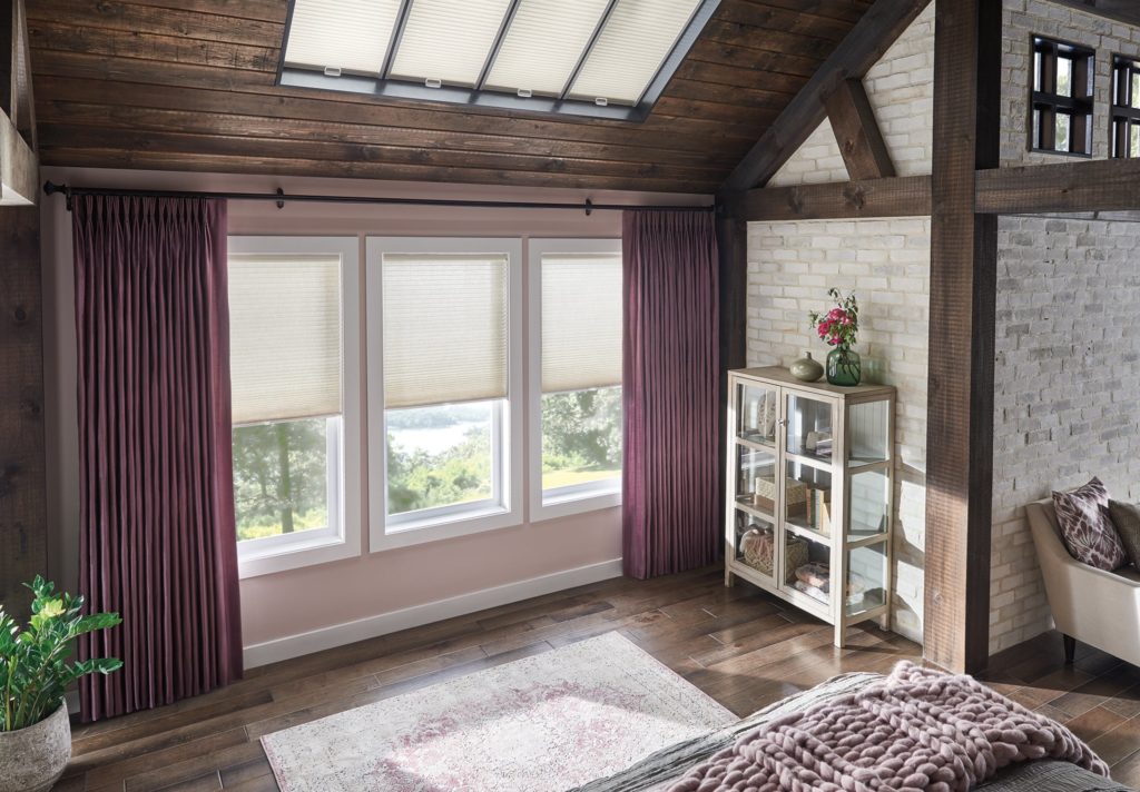 A cozy bedroom with a skylight illuminating a comfortable bed & window coverings, creating a serene and inviting atmosphere.